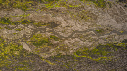 Braided glacial river Iceland aerial with winding streams cutting across volcanic land and rocky terrain with green moss covered areas