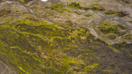 Top view Iceland braided river system with glacial meltwater running across volcanic landscape brown rocky valley and patches of moss