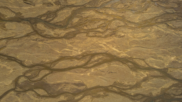 Aerial view of braided river system in Iceland flowing across volcanic sand plains creating abstract natural patterns in the landscape