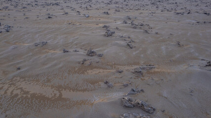 Close aerial view of Icelandic geothermal area showing mud textures and scattered rocky mineral deposits