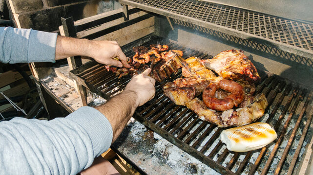 Chef grilling meat and sausages on barbecue for outdoor party