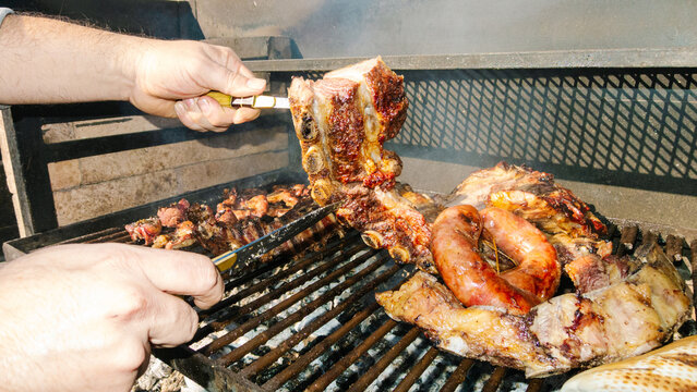 Chef grilling ribs and sausages on barbecue grill