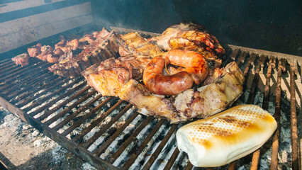 Argentinian asado cooking on a grill with bread and chorizo
