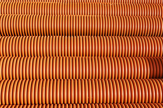 Curved Orange Drainage Pipes Arranged in a Neat Pattern Outdoors