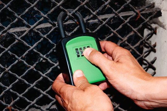 close-up of a man setting the code on a green lockbox on metal grate
