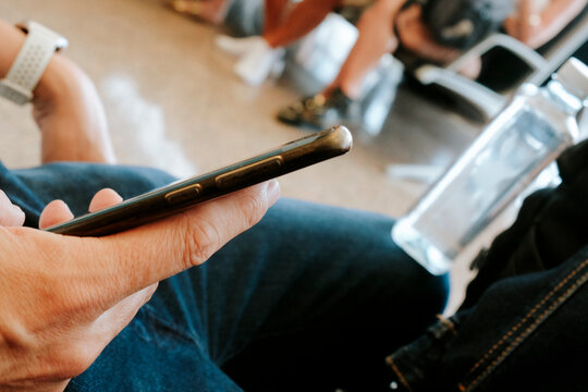 a man checks his phone as he waits at a busy airport terminal