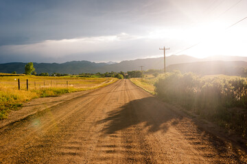 Dirt road crossing a field with a landscape in the background