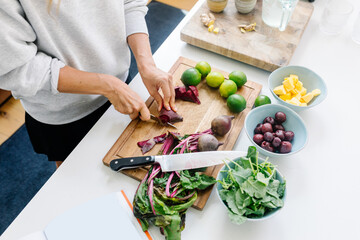 Anonymous person using a knife to chop beets on their kitchen