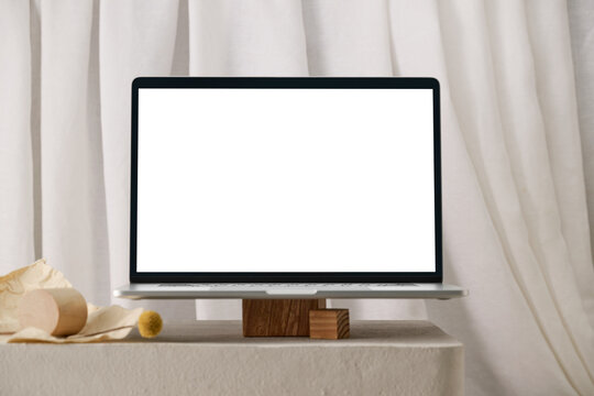 A laptop with a blank screen rests on a wooden with minimalist setting