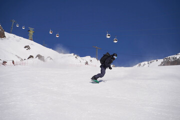 Snowboarder carving down sunny alpine slope