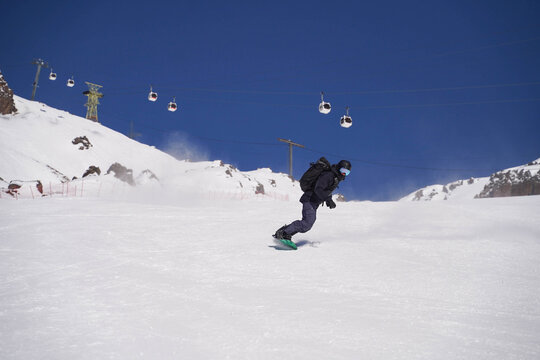 Snowboarder carving down sunny alpine slope