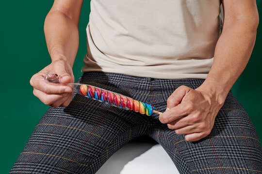 man unwrapping a spiral lollipop while sitting on a chair
