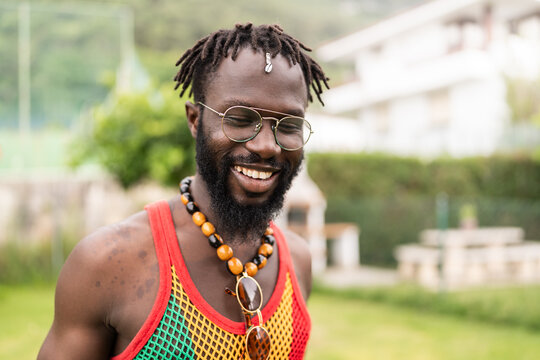 Happy jamaican man wearing tank top and necklace smiling outdoor