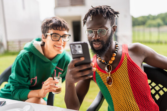 Friends using mobile phone while having breakfast outdoors