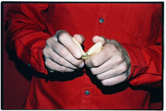 a man in red cracking open a fortune cookie by hand, 35mm