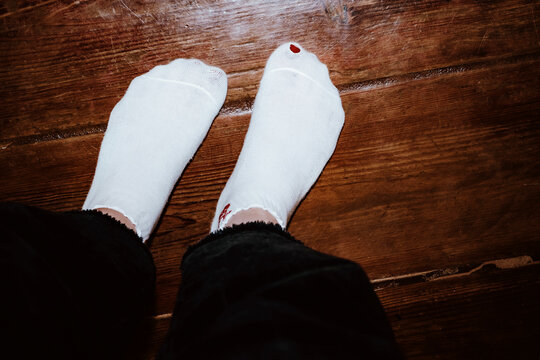 White Socks With a Hole on Wooden Floor in Cozy Indoor Space