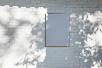 White Brick Wall with Framed Canvas and Leaf Shadows