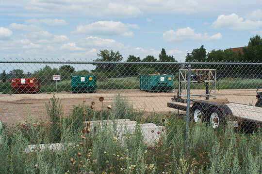 Fenced Industrial Waste Site with Dumpsters and Trailer
