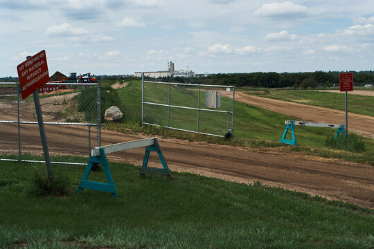 Restricted Dirt Road Entrance with Warning Signs and Fencing
