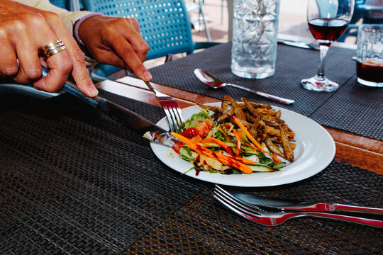 a woman cuts salad beside a plate of spanish pescaito frito
