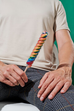 seated man holds a wrapped twisted rainbow lollipop