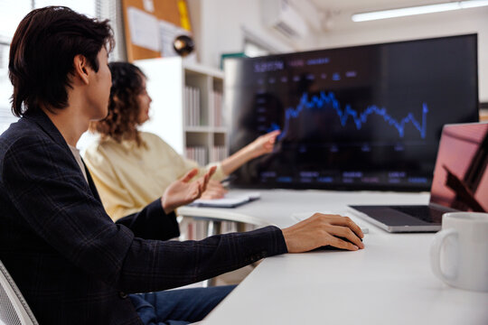 Business meeting analyzing stock market data on a screen.