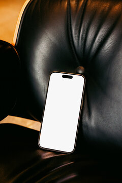 Smartphone with white screen Mockup on Black Leather Chair
