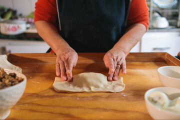 Woman pressing dough in a beef empanada preparation