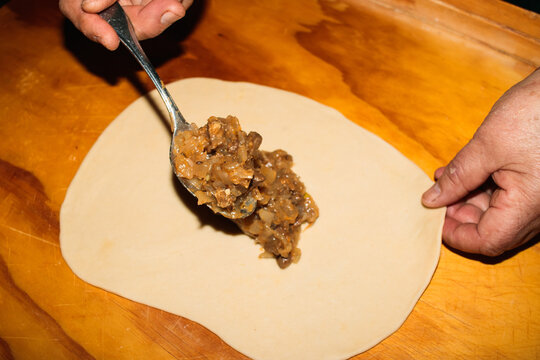 Unrecognizable person spooning beef and onion mixture onto pastry