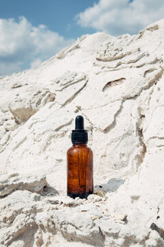 Amber dropper bottle on white rocks


