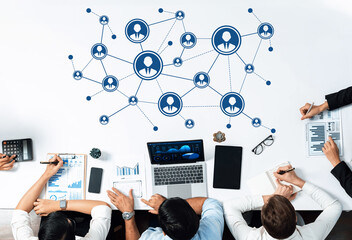 A diverse group of professionals collaborates over a workspace featuring digital connections. They analyze data through charts and graphs, emphasizing teamwork and strategic planning. Amity