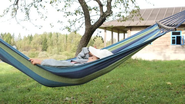 Child relaxing in hammock on summer day