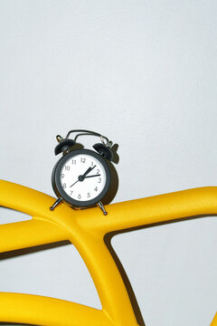 Clock on a Vibrant Yellow Surface Against a Gray Wall with Copy Space