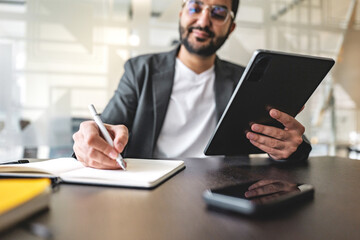 Man uses tablet and notebook for notes at work in office