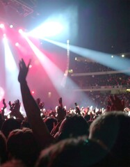 A vibrant concert crowd raises their hands in excitement