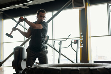 Young Biracial Man Using Sledgehammer in Gym