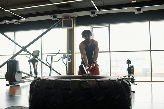 Man with Curly Hair Slamming Tire with Sledgehammer