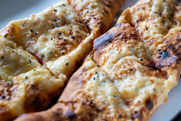 Two pieces of pizza with cheese and sesame seeds