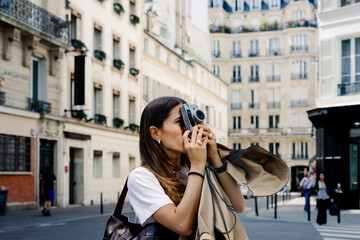 A tourist using a retro camera to take photos while walking in Paris