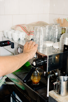 Hand of an unknown barista using a coffee maker to prepare an espresso