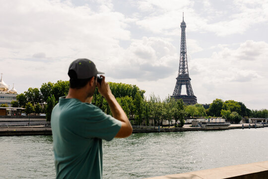 A tourist using his camera to take photos of the Eiffel Tower