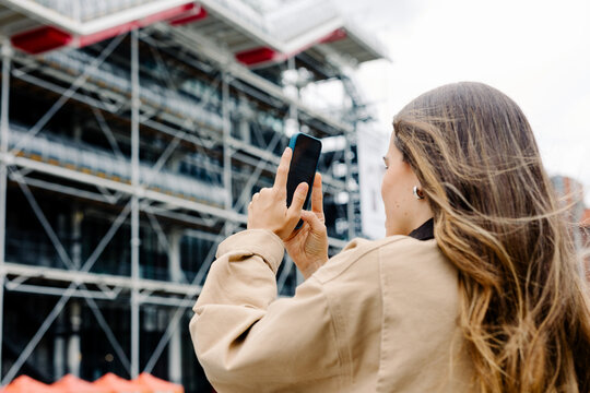 Tourist using her smartphone to take photos while strolling in Paris