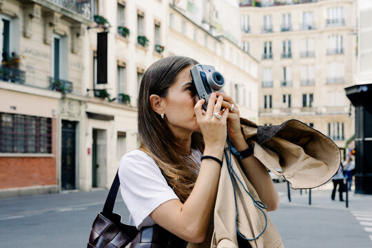 A traveler holding a vintage camera while capturing images along Paris