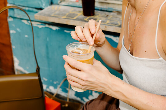 Close up with flash of an unknown woman drinking an iced coffee to go