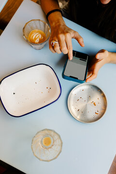 Hands of an anonymous tourist using her smartphone after breakfast
