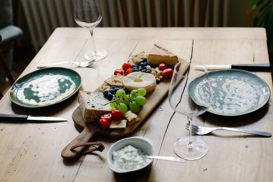 Dining setup indoors with wine cups, uncooked salmon and sliced cheese