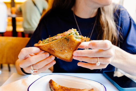 Unknown woman enjoying a sandwich during breakfast at a caf&eacute; in Paris