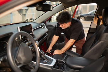 Man Cleaning Interior of Car in Urban Setting 