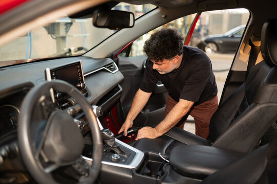 Man Cleaning Interior of Car in Urban Setting 