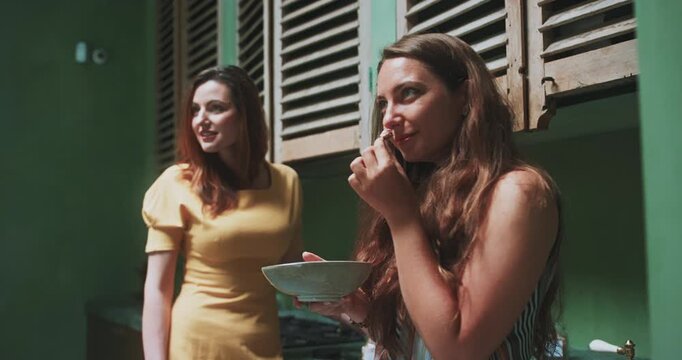 Women chatting in studio kitchen while smelling tea leaves